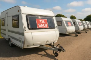 Række af brugte campingvogne til salg hos dansk campingforhandler på sommerdag.